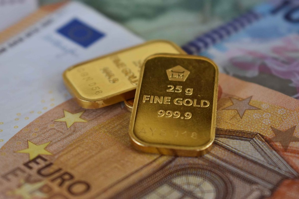 Two small gold bars stamped fine gold resting on Euro banknotes